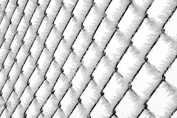 Frozen chain link fence covered with dense frost creating graphic winter texture and repeating icy pattern
