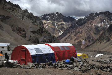 Tent camp set up by climbers in winter. Tourists and scientists in bare mountains. Temporary winter camp in snowy mountains.