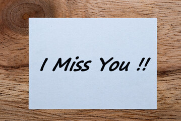 The words "I Miss You" were written on a piece of white paper on a wooden table.