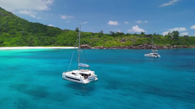 Travel and vacation on yacht in tropical countries, La Digue Island. Aerial shot of catamaran in bay with clear turquoise water in the Seychelles. Sailboats float near tropical island