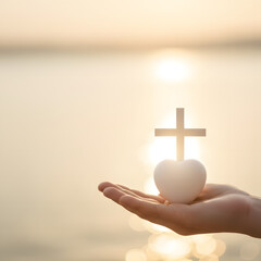 Hand holding heart and cross symbol against sunlit water background  