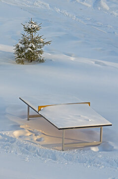 A tennis table under a thick layer of snow in a winter park