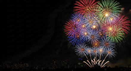 Colorful fireworks explode over a dark night city skyline, multicolored bursts lighting the sky as people celebrate festive New Year 2026 in a vibrant urban atmosphere