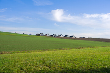 Rural landscape with agriculture field and single family detached homes in the background on a sunny autumn day. Photo taken December 20th, 2025, Oberh&ouml;ri, Canton of Zurich, Switzerland.
