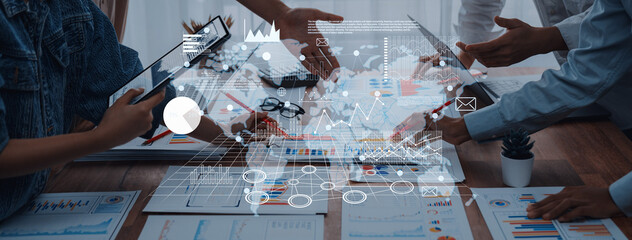 Engaging business meeting featuring hands shaking over charts and digital data visuals on a wooden desk, representing collaboration and strategic planning in a professional setting. Trope