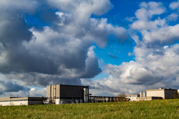 Industrial factory landscape in manufacturing area under blue cloudy sky.