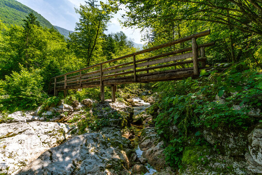 Serene wooden bridge crossing Lepenjica River towards Sunik Waterfalls in Slovenias Soca Valley