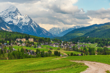 Cortina d'Ampezzo town with alpine meadows, scattered houses and snow covered Dolomiti Alps mountains. Italian Dolomites in Belluno region, Italy. Alpine landscape. Travel and touristic destination