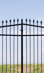 metal gate with spears against sky