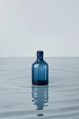 Minimalist blue glass bottle floating on rippling water surface with soft background