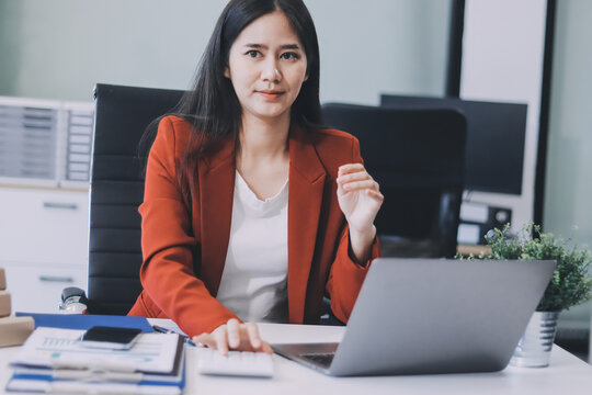 Asian business woman working on a laptop in a professional office - Powered by Adobe