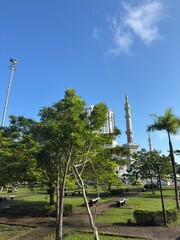 View of a serene city park with majestic towers under a brilliant clear blue sky.
