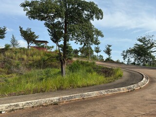 The winding road climbs through lush green landscapes under clear skies with shadows in the distance.