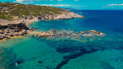 Obraz premium People enjoy a sunny day at a beautiful wild beach in Greece, surrounded by turquoise waters, sandy shores, and rocky formations perfect for a relaxing vacation.