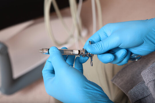 Anesthesia in dentistry. The syringe is in the doctor's hands. Dental syringe for anesthesia. The concept of modern medicine. Close-up.