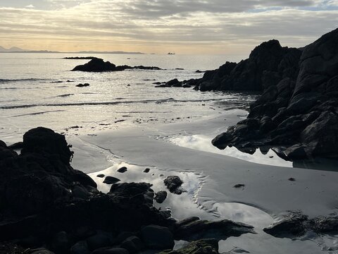 Beautiful wild beach Isle of Mull Scotland Uisken the beautiful rocky and sandy shore sunrise with water pools reflect sun light  vast ocean on horizon with wildlife  and blue sky in Winter no people