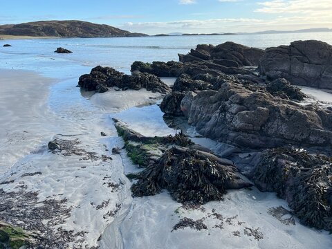 Beautiful wild beach Isle of Mull Scotland Uisken the beautiful rocky and sandy shore sunrise with water pools reflect sun light  vast ocean on horizon with wildlife  and blue sky in Winter no people