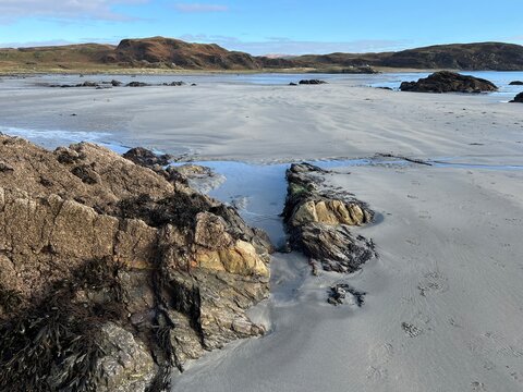 Beautiful wild beach Isle of Mull Scotland Uisken the beautiful rocky and sandy shore sunrise with water pools reflect sun light  vast ocean on horizon with wildlife  and blue sky in Winter no people