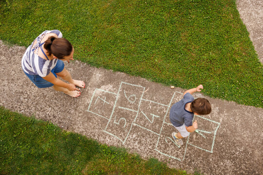 Mother and toddler son having fun playing hopscotch game