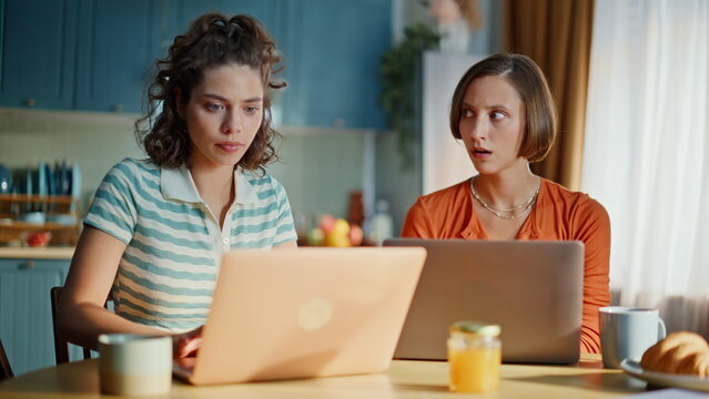 Two losers watching laptop sitting apartment kitchen closeup. Stressed brunette