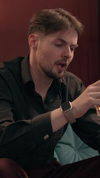 Depressed angry Caucasian male gambler smoking cigar throwing poker card losing casino game mad gamer man guy playing wager lost failure bet drink whiskey unhealthy habit alcoholism gambling at home