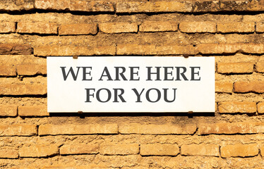 Fototapeta premium Support, help and we are here for you symbol. Concept words We are here for you on beautiful white marble sign plate. Beautiful brick wall background. Business we are here for you concept. Copy space.