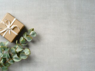 Elegant gift box on warm grey linen with eucalyptus leaves for minimalist design