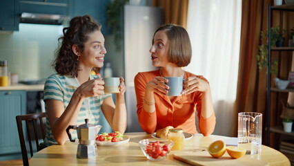 Lesbain couple breakfasting together enjoying communication in kitchen closeup.