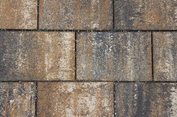 Fototapeta premium Textured paving stones in earthy tones create a rustic surface pattern, showcasing the natural wear and weathering of the materials in an outdoor setting