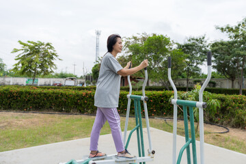 A woman exercising on outdoor fitness equipment in a village park, showing healthy lifestyle, daily workout routine, physical activity, community wellness, and active living.