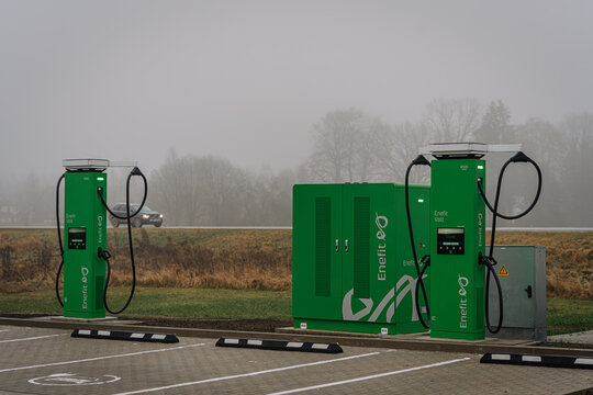 Riga, Latvia - December 19, 2025: Electric vehicle charging station with Enel X branding in a foggy landscape near a highway