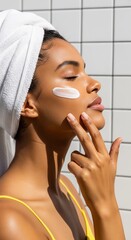 
Radiant woman in a towel wrap applies face cream in the sun. A serene skincare moment promoting self-love and glowing beauty against a tiled background