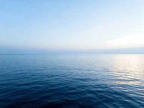 Calm ocean surface under clear sky at sunrise or sunset - Powered by Adobe