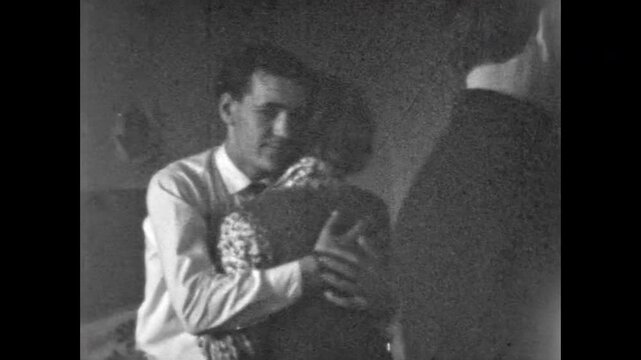 Young couples dancing slow dance indoors. Happy men, women together in close connection. Youthful romantic in home interior. Tenderness in love relationships. Old film. Archival retro. Vintage archive