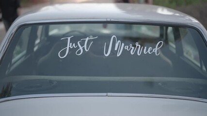 Close-up shot of a Just Married sign on a car window after a wedding ceremony. Romantic symbol of newlyweds, celebration of love, marriage announcement and joyful beginning.