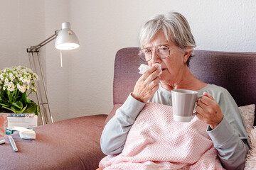 Elderly Caucasian woman with severe cold symptoms and fever, similar to seasonal flu or pollen...