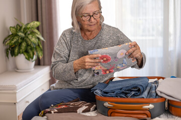 Full suitcase concept, senior woman packing, suitcase full of clothes on bed. Travel concept, fear of forgetting items, senior lifestyle, vacation preparation.