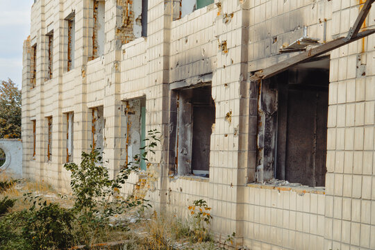 Exterior of a civilian building in Ukraine damaged by shelling. The walls show bullet holes, broken windows and burn marks from fire after the attack