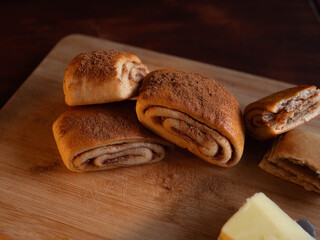 Freshly baked cinnamon rolls dusted with spice on a rustic wooden board with butter