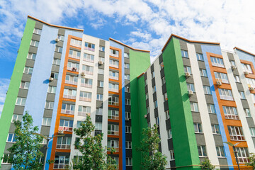 Modern apartment block with vibrant green blue and orange facade design at the final construction stage under a blue sky. New real estate concept © Oleksandr Baranov