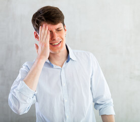 Young man experiencing acute headache in living room