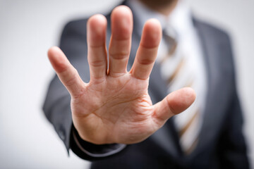 Obraz premium Businessman in suit extending hand towards camera with palm open expressing stop or halt gesture with blurred background and tie visible