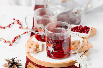 Red winter tea in glass cups on wooden board with festive decor. Cozy seasonal drink and clean holiday table styling.