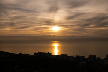 Fototapeta premium Dramatic sunset over the sea with the silhouette of buildings.