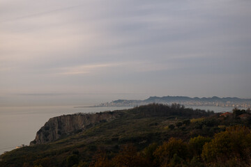 Fototapeta premium Misty coastal landscape with a city in the distance