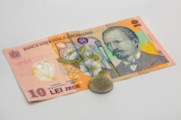 Romanian ten lei banknote with coin closeup on white background