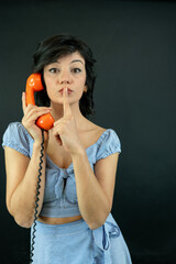 Woman Holding Retro Phone Making Silence Gesture. Secret Communication Concept