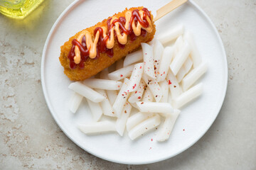 Garaetteok or korean traditional snack served with a corn-dog on a white plate, horizontal shot, elevated view
