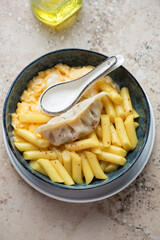 Bowl of korean tteokbokki or garaetteok with steamed dumpling and egg, vertical shot on a beige granite background