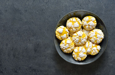 Lemon crinkle cookies in bowl on blue stone background with free space